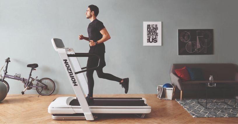Ein Mann läuft auf einem Laufband im Wohnzimmer