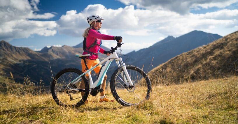 Eine Person steht mit einem Fahrrad in einer bergigen Landschaft