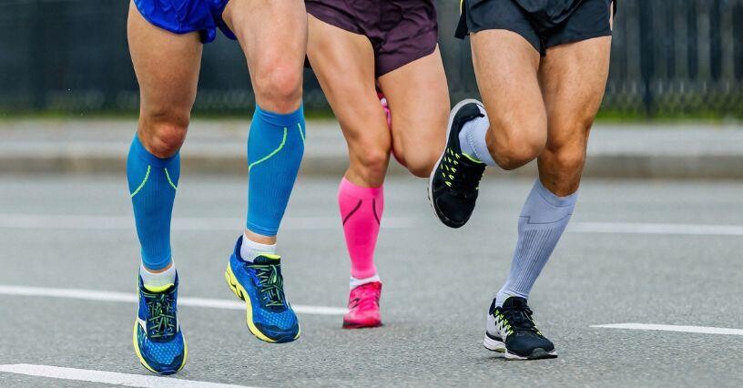 Drei Personen tragen Sportkompressionssocken beim Laufen auf der Straße