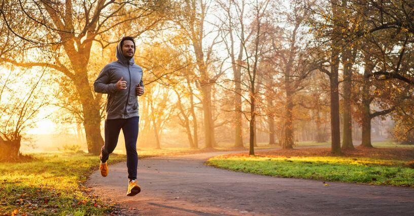 Ein Mann joggt im Park bei Sonnenaufgang