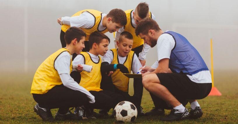 Trainer erklärt jungen Fußballern beim Training Übungen